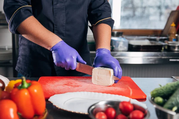 Tiro recortado de chef rebanando queso en la cocina — Stock Photo