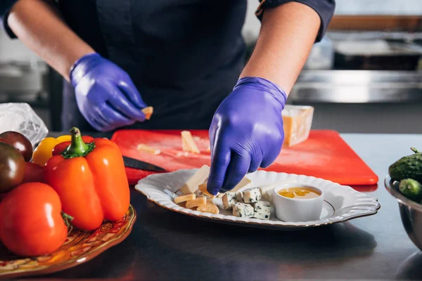 Обрізаний знімок шеф-кухаря, який кладе сирні скибочки на тарілку — стокове фото
