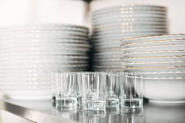 Close-up shot of stacked clean tableware and glasses at restaurant — Stock Photo