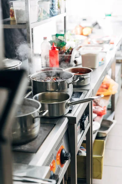 Variación de platos hirviendo en sartenes de salsa en la cocina del restaurante - foto de stock