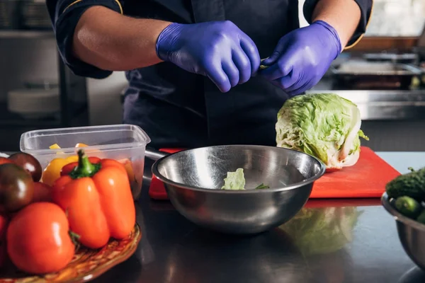 Tiro recortado de chef cocinar verduras en el lugar de trabajo en el restaurante - foto de stock