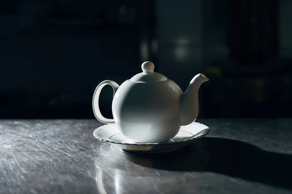 Вінтажний чайник на тарілці на металевій поверхні в темній кімнаті — стокове фото