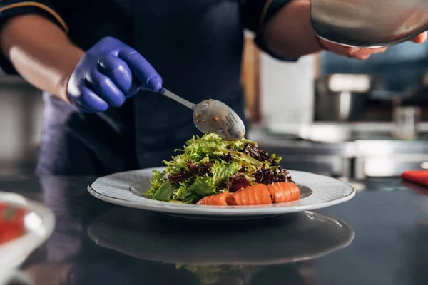 Colpo ritagliato di chef versando salsa su insalata da cucchiaio — Foto stock