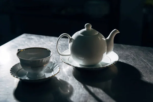 Tetera vintage una taza en la superficie de metal en habitación oscura - foto de stock