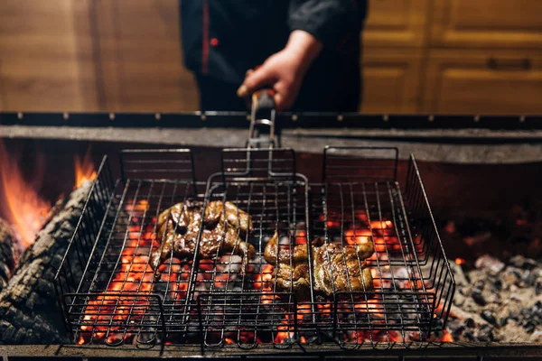 Tiro recortado de chef cocinar carne en llamas en la barra de la parrilla - foto de stock
