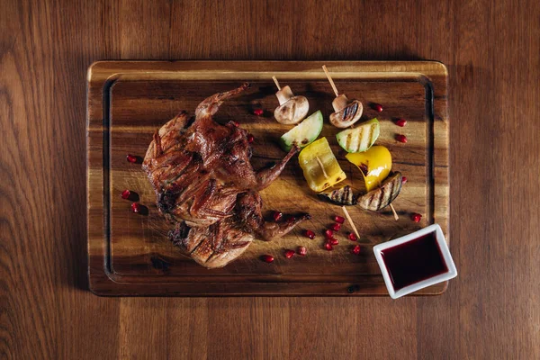 Vista superior de la deliciosa codorniz asada con verduras servidas en tablero de madera - foto de stock