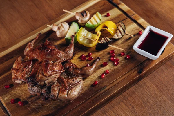 Close-up shot of roasted quail with vegetables served on wooden board — Stock Photo