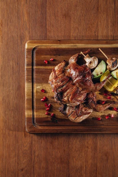 Vista dall'alto di deliziose quaglie arrosto con verdure servite su tavola di legno — Foto stock