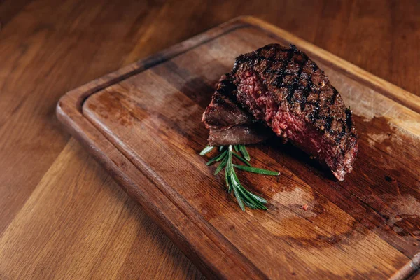 Medium rare grilled steak on wooden board — Stock Photo