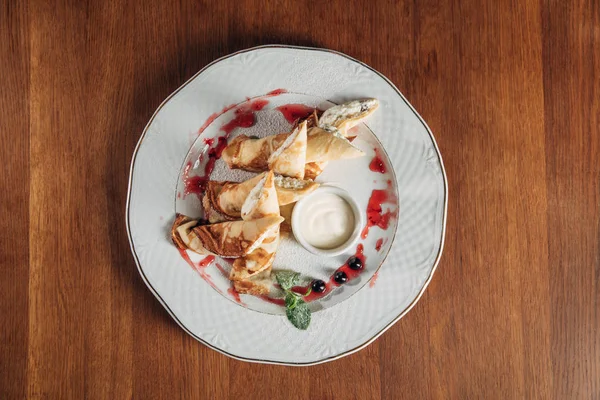 Vista dall'alto di crepes arrotolate con ricotta servita su piatto bianco con marmellata — Foto stock