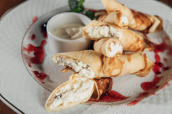 Primer plano de crepes laminados con requesón servido en plato blanco con mermelada - foto de stock