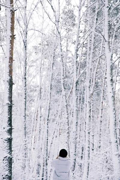 Rückansicht eines Mädchens, das im verschneiten Wald spaziert — Stockfoto