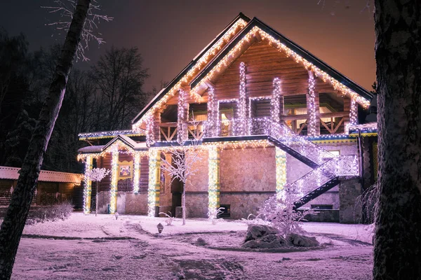 Maison en bois avec guirlandes en soirée en forêt — Photo de stock