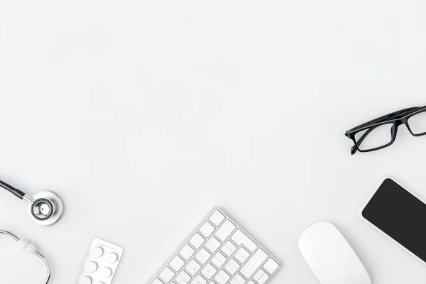 Clavier entouré de lunettes, souris d'ordinateur, stéthoscope isolé sur fond blanc — Photo de stock