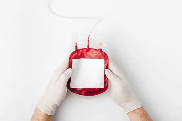 Top view of hands in gloves holding blood for transfusion isolated on white background — Stock Photo