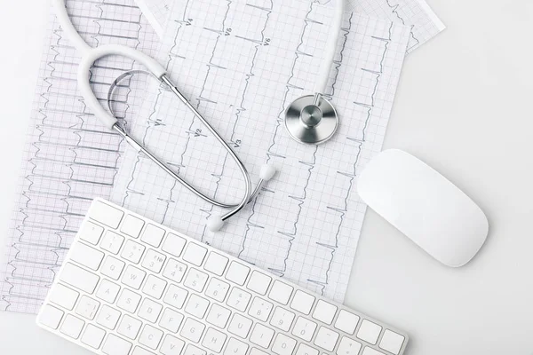 Stéthoscope, clavier et souris d'ordinateur posés sur papier avec cardiogramme isolé sur fond blanc — Photo de stock