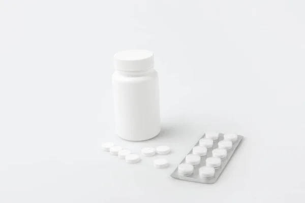 Container, scattered pills  and tablets in package isolated on white background — Stock Photo