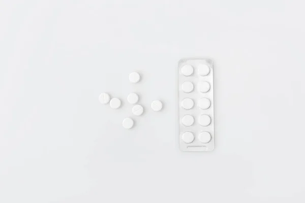 Pastillas y tabletas dispersas en el paquete aislado sobre fondo blanco — Stock Photo