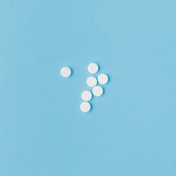 Scattered white pills isolated on blue background — Stock Photo