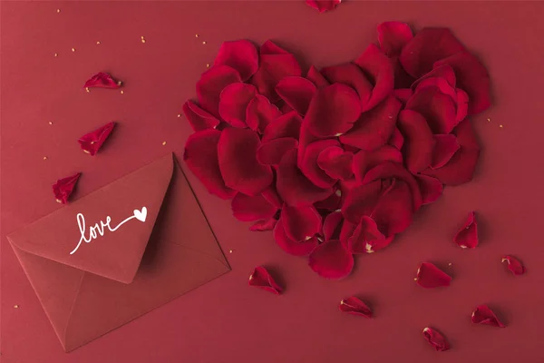Вид зверху на серце з пелюсток троянд і конверт ізольовані на червоному, концепція дня Святого Валентина — Stock Photo