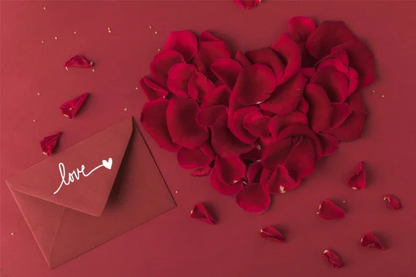 Vista superior do coração feito de pétalas de rosas e envelope isolado no conceito dia vermelho, st valentines — Fotografia de Stock