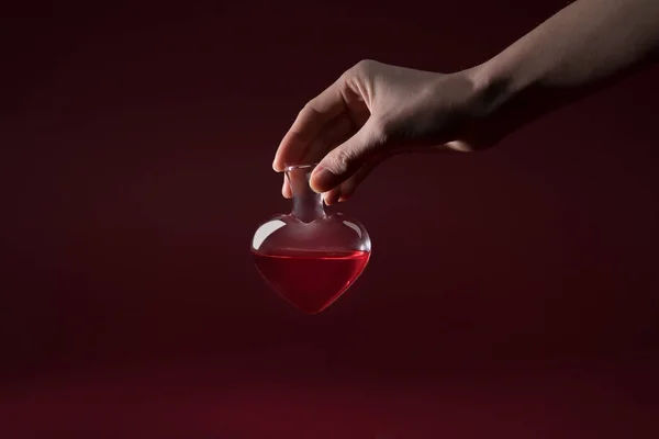 Обрізане зображення жінки, що тримає скляну банку кохання зілля ізольовано на червоному — стокове фото