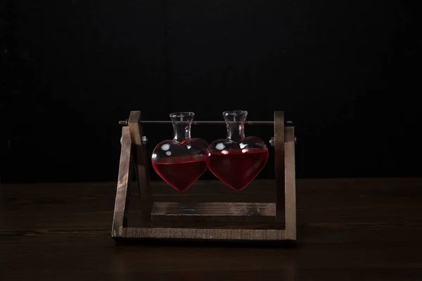 Dos frascos de vidrio en forma de corazón con perfume rosa - foto de stock