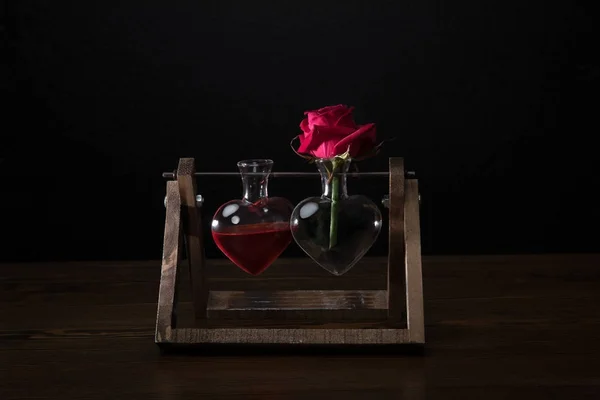 Red rose in heart shaped vase and vase with love elixir — Stock Photo