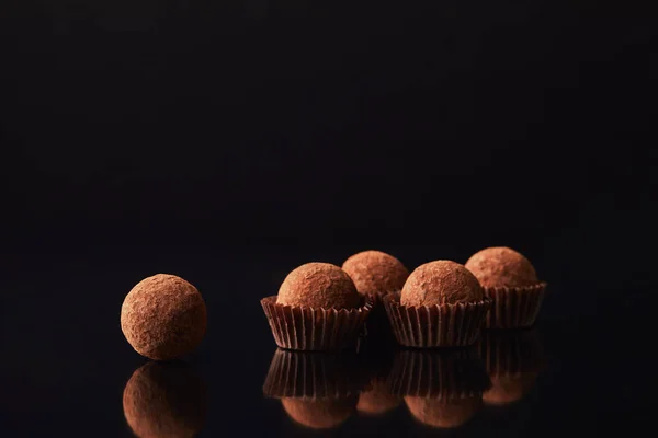 Vista de perto de trufas saborosas em preto — Fotografia de Stock