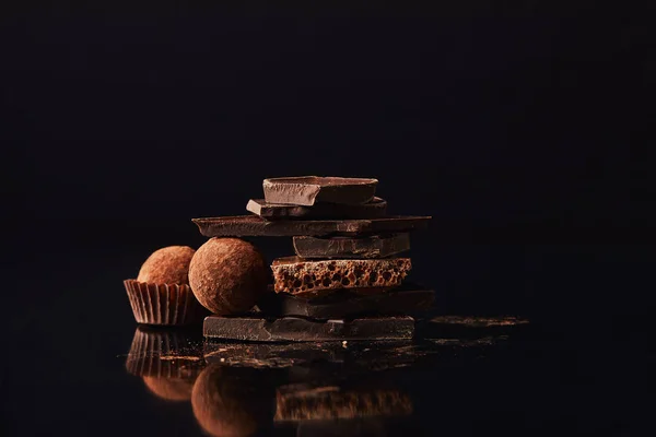 Vista de cerca de la disposición de trufas y barras de chocolate en negro - foto de stock