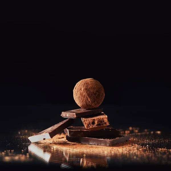 Vue rapprochée de la truffe sur barres de chocolat avec poudre de cacao sur noir — Photo de stock