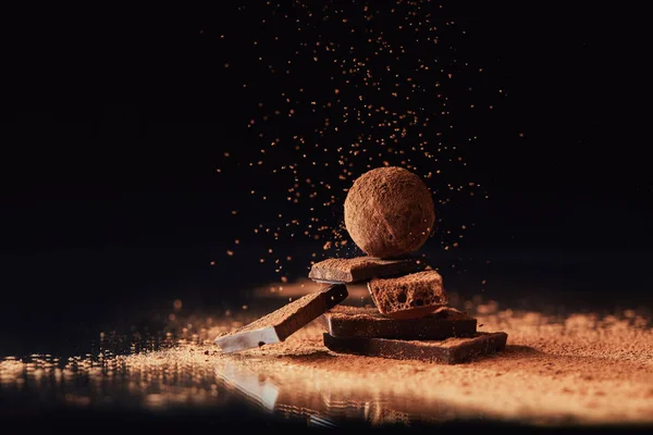 Vista de perto da trufa em barras de chocolate com cacau em pó em preto — Fotografia de Stock