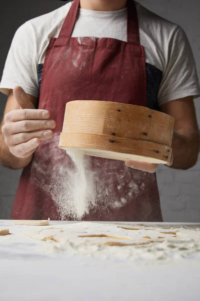 Image recadrée du chef tamisant la farine avec tamis — Photo de stock