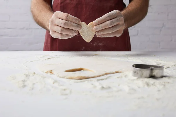 Abgeschnittenes Bild des Chefs mit herzförmigem Stück Teig in der Hand, Valentinstag-Konzept — Stockfoto