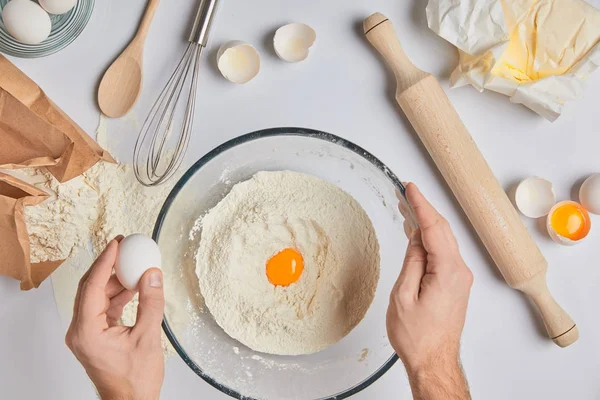 Обрізане зображення шеф-кухаря, що додає яйця до борошна — стокове фото