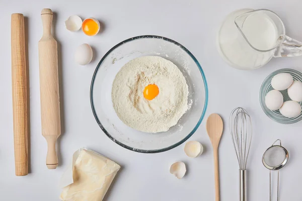 Top view of glass bowl with flour and egg on tabletop — Stock Photo