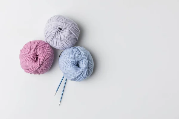 Vue de dessus des boules de fil coloré et des aiguilles à tricoter isolées sur blanc — Photo de stock