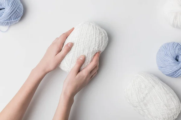 Cropped view of woman holding white yarn ball in hands on white background — Stock Photo