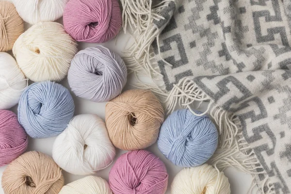 Scattered colored yarn balls and blanket  on white background — Stock Photo