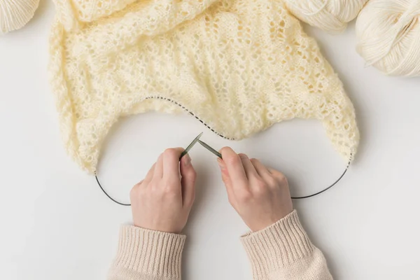 Vista ritagliata della donna che lavora a maglia lana bianca con aghi su sfondo bianco — Foto stock