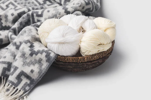 White yarn balls in wicker basket with blanket isolated on white — Stock Photo