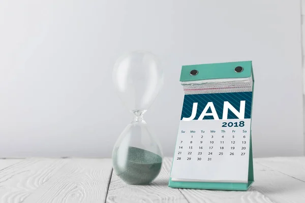 Close up view of hourglass and january calendar on wooden tabletop isolated on white — Stock Photo