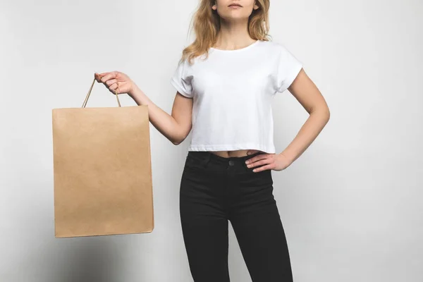 Recortado tiro de mujer en blanco camiseta en blanco con bolsa de compras - foto de stock