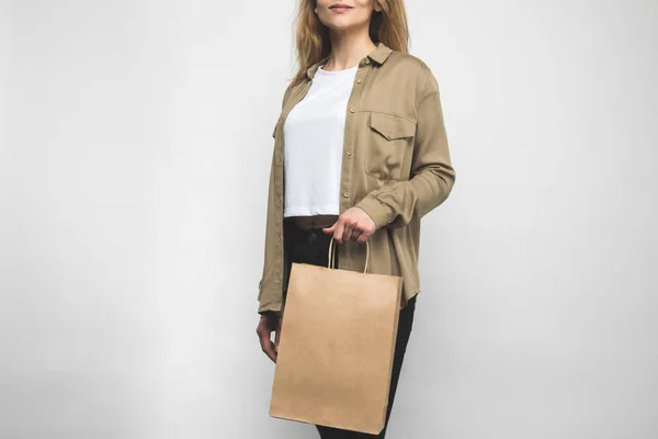 Молода жінка в модній сорочці на білому з сумкою для покупок — стокове фото