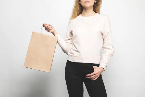Обрезанный снимок женщины в пустой толстовке на белом с пакетом покупок — стоковое фото