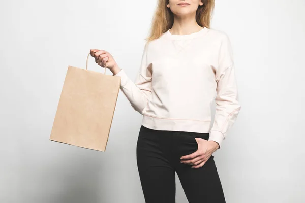 Recortado tiro de mujer en sudadera en blanco en blanco con bolsa de compras - foto de stock