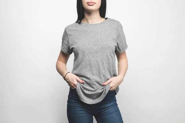 Recortado tiro de mujer joven en blanco camiseta gris en blanco - foto de stock