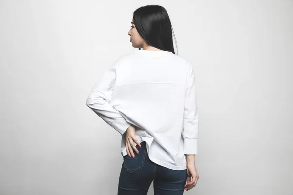 Vista trasera de mujer joven en sudadera en blanco sobre blanco - foto de stock