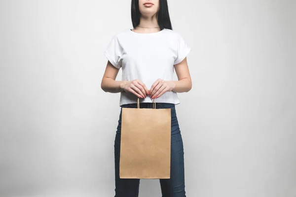 Young woman in blank t-shirt on white with shopping bag — Stock Photo