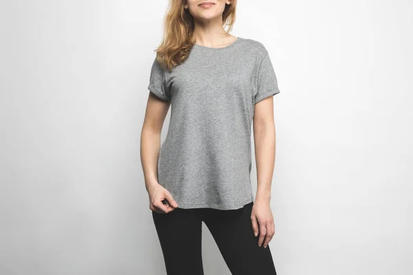 Tiro recortado de atraente jovem mulher em branco cinza t-shirt isolado no branco — Fotografia de Stock